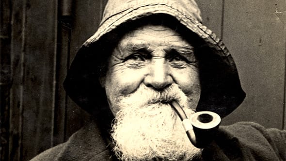 An old wrinkly man smoking a pipe.
