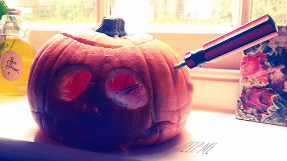E decomposing pumpkin with a screwdriver driven through its fleshy head.
