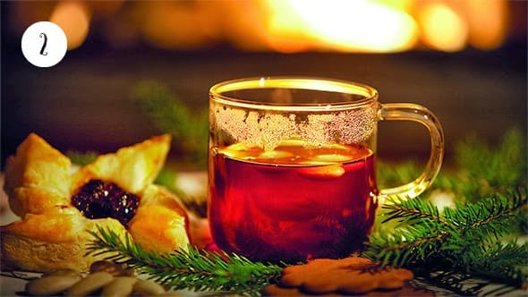 A glass of mulled wine in a beautiful Christmas setting, open fire in the background.