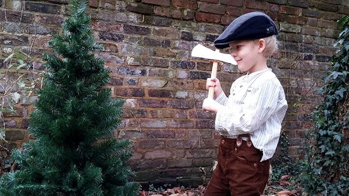 Child pretending to chop down plastic Christmas tree
