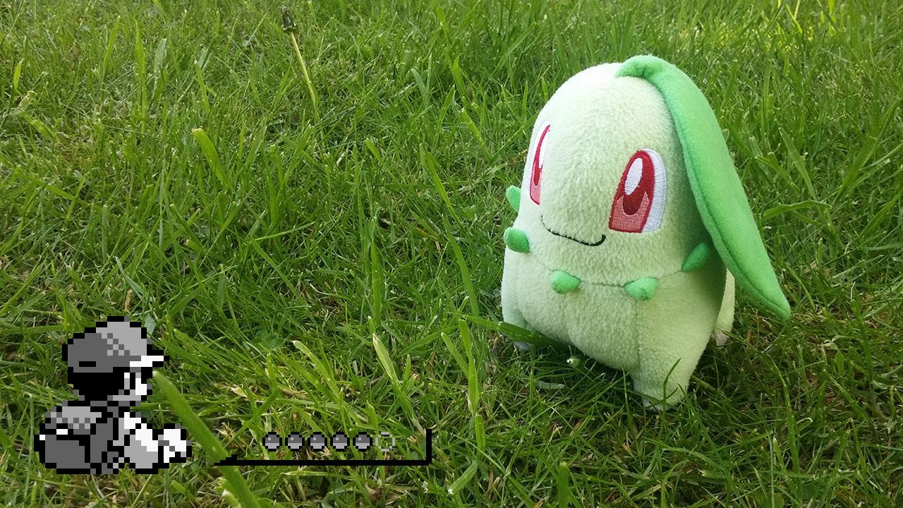 Chikorita plushie sitting in luscious green grass.