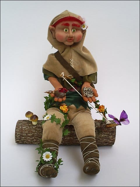 Elf doll sitting on wooden log