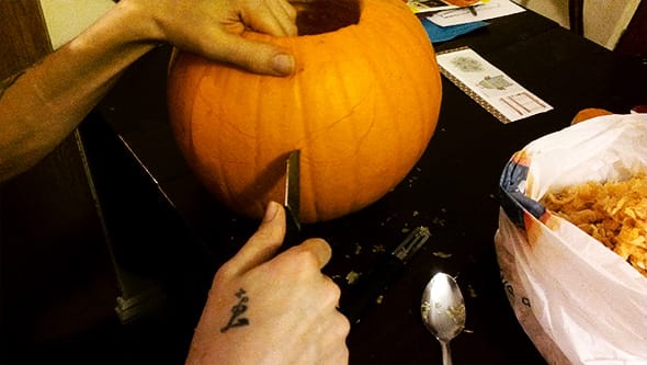 Carlos carving a pumpkin with a terribly unsharp fruit knife.