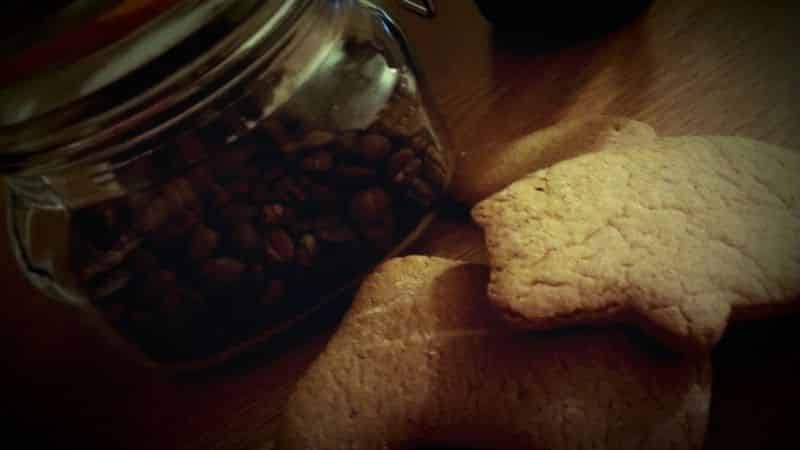 Close-up of gingerbread cookies and coffee beans in a glass jar. 
