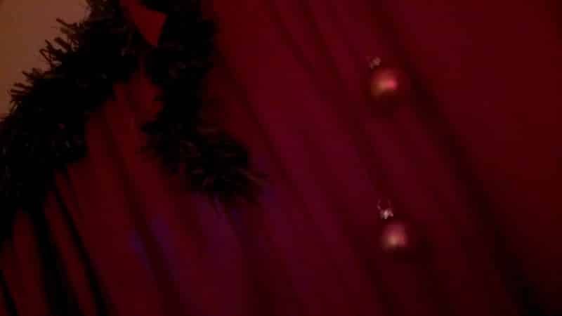 Christmas garland and baubles hanging off a window-curtain.
