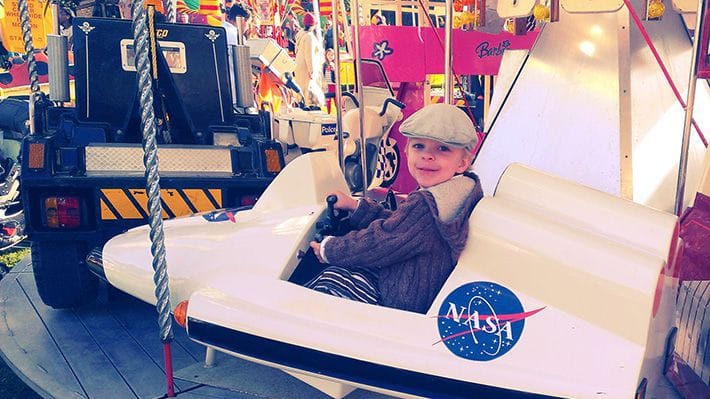 Lucien riding a spaceship on a merry-go-round