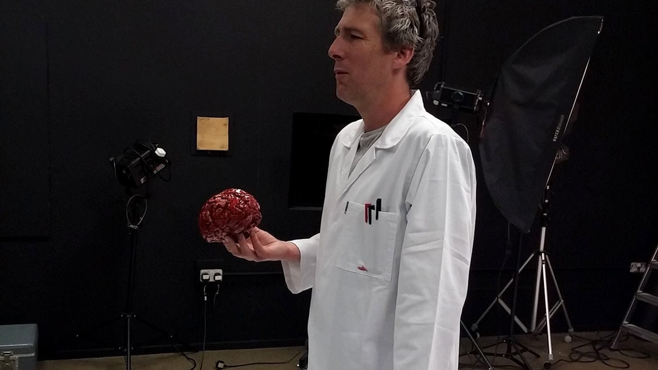 Kris standing and posing my the blood-covered brain.