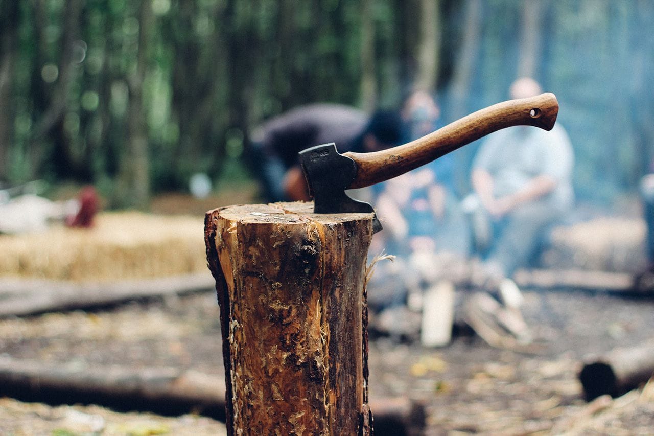 An axe lodged in a piece of wood.