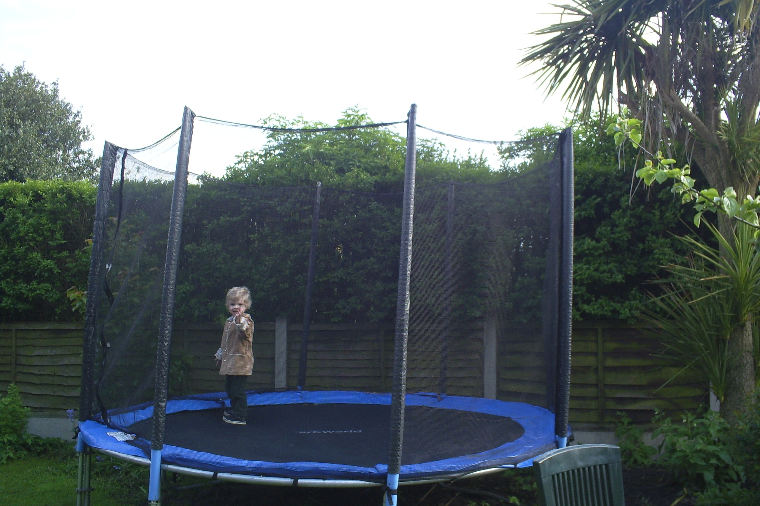 Lucien, 3-years-old, standing on a big blue trampoline in the backgarden of the first accommodation we rented for 2 weeks, having just moved to the UK.